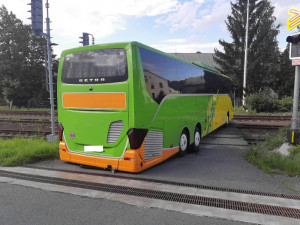 Řidič autobusu se chtěl vyhnout komplikacím na dálnici, tak z ní sjel. Uvízl ale na přejezdu