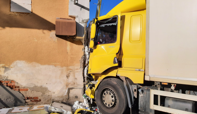 Nepozornost za volantem. Řidička v náklaďáku vyjela mimo silnici a narazila do budovy
