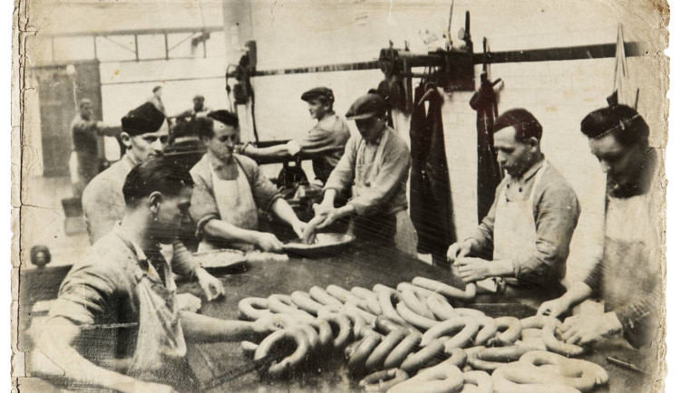 Jeden z dílenských provozů masny v Kostelci po roce 1920. Řezníci ručně zpracovávají velmi žádaný točený koňský salám. Foto: Poskytl Stanislav Jelínek
