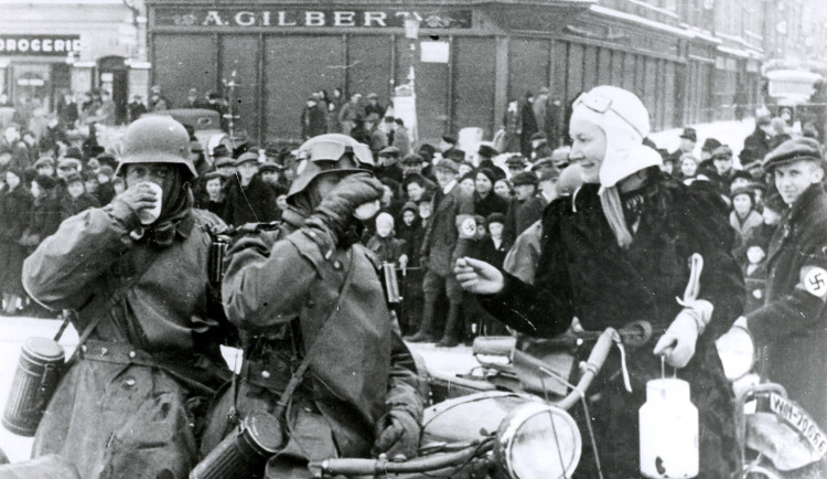 Jihlavské náměstí dopoledne 15. března 1939. Žena přinesla německým vojákům něco pro zahřátí.