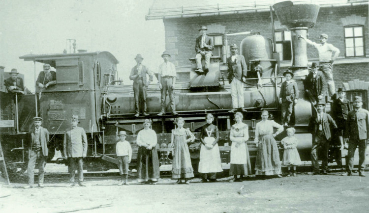 Památeční focení zaměstnanců rakousko-uherské státní dráhy s manželkami a dětmi na vlakovém nádraží Jihlava město. Kolem roku 1900 mezi pracovníky dráhy velmi populární akce.