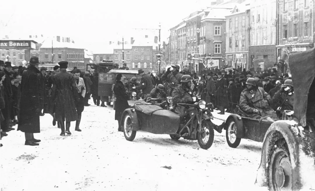 Němečtí vojáci přijeli. Dav sleduje jejich počínání před prodejnou Gilbert na západní straně náměstí. Reprofoto: poskytl Stanislav Jelínek