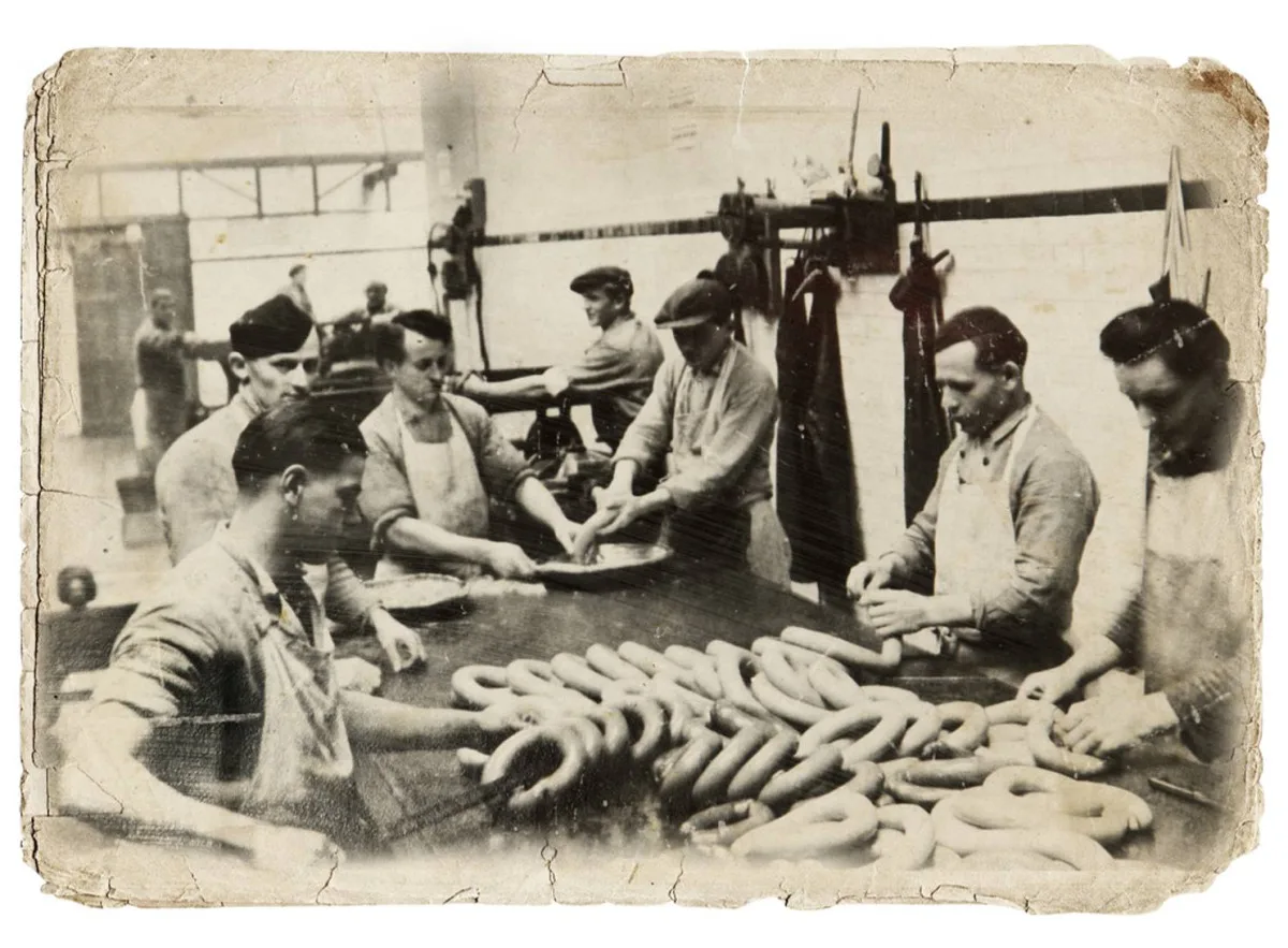 Jeden z dílenských provozů masny v Kostelci po roce 1920. Řezníci ručně zpracovávají velmi žádaný točený koňský salám. Foto: Poskytl Stanislav Jelínek