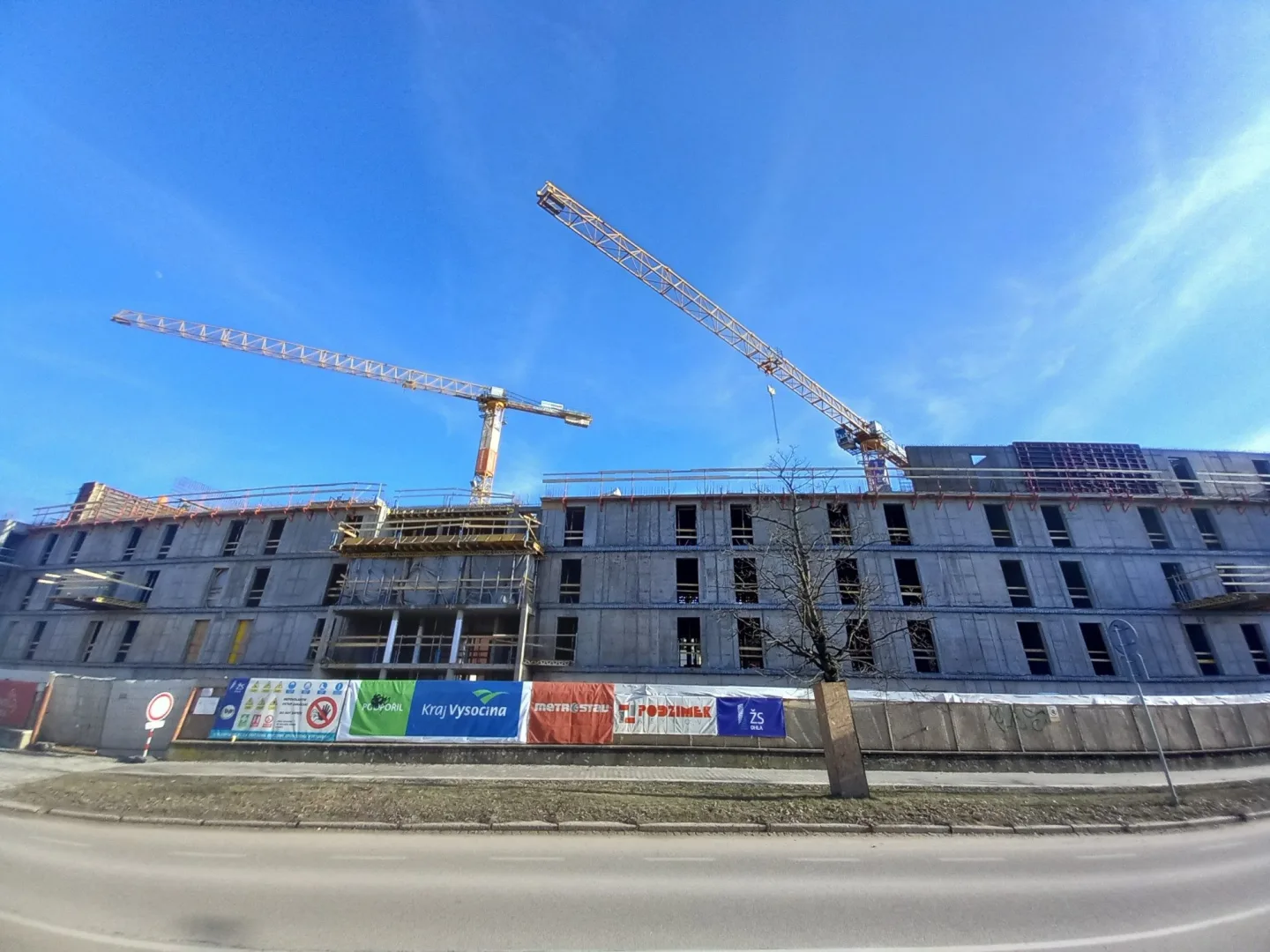 FOTO: Dělníci staví poslední patro vysokoškolských kolejí, soudní spory pokračují