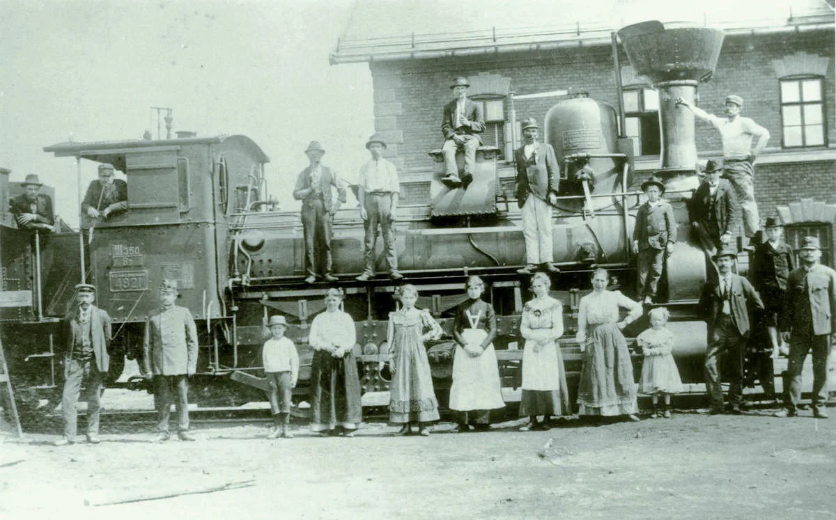 Památeční focení zaměstnanců rakousko-uherské státní dráhy s manželkami a dětmi na vlakovém nádraží Jihlava město. Kolem roku 1900 mezi pracovníky dráhy velmi populární akce.
