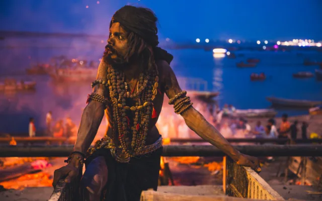 Aghori a za ním hořící kremační oheň ve Varansí