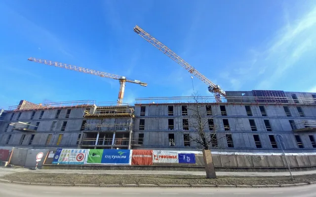 FOTO: Dělníci staví poslední patro vysokoškolských kolejí, soudní spory pokračují
