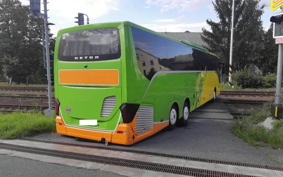 Řidič autobusu se chtěl vyhnout komplikacím na dálnici, tak z ní sjel. Uvízl ale na přejezdu