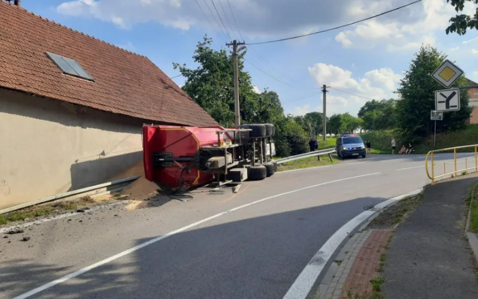 Mladý traktorista nezvládl průjezd zatáčkou, na dům a silnici vysypal 16 tun pšenice