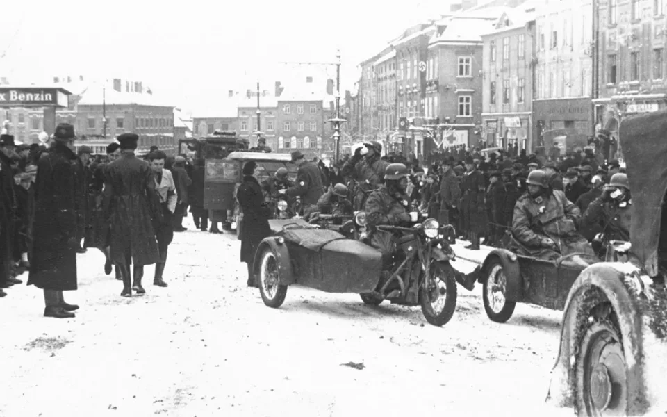 Němečtí vojáci přijeli. Dav sleduje jejich počínání před prodejnou Gilbert na západní straně náměstí. Reprofoto: poskytl Stanislav Jelínek