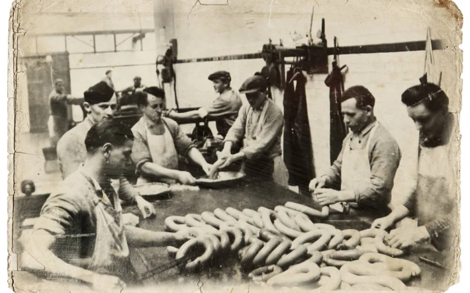 Jeden z dílenských provozů masny v Kostelci po roce 1920. Řezníci ručně zpracovávají velmi žádaný točený koňský salám. Foto: Poskytl Stanislav Jelínek