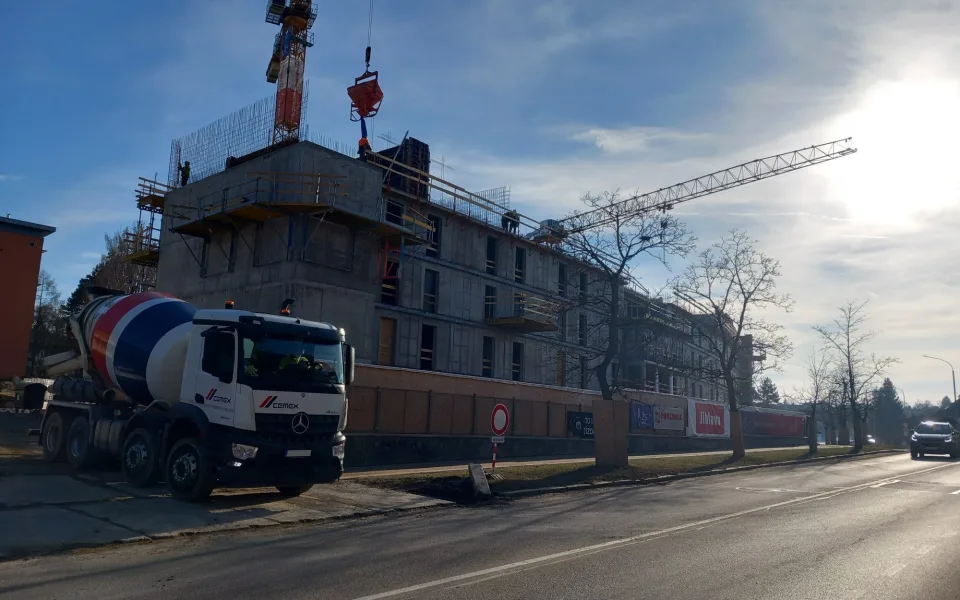 FOTO: Dělníci staví poslední patro vysokoškolských kolejí, soudní spory pokračují