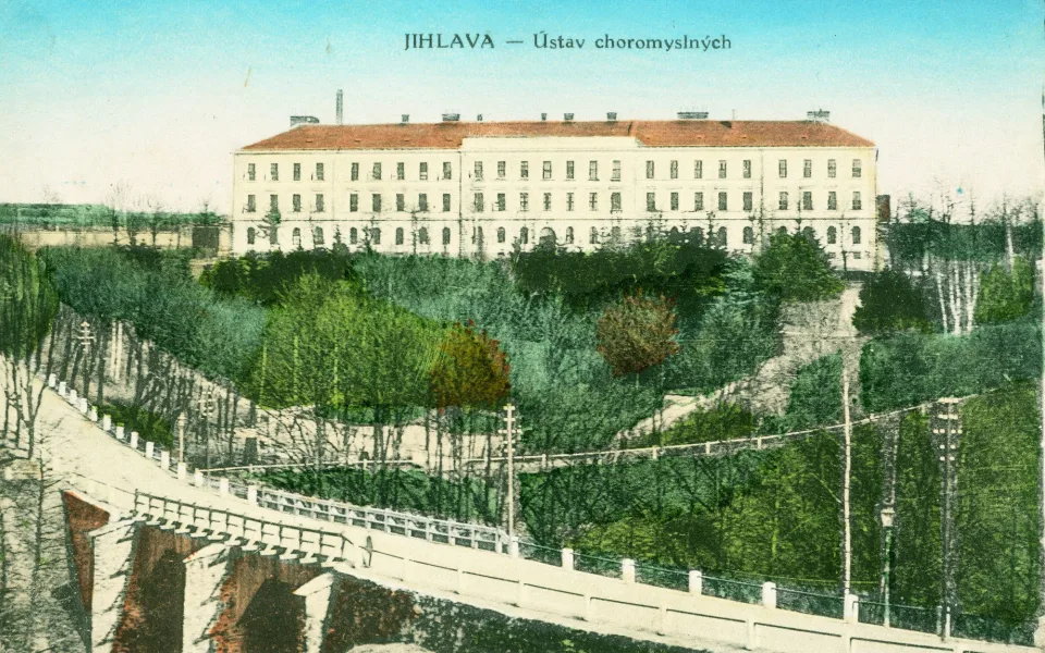 Hlavní budova Ústavu choromyslných v Jihlavě kolem roku 1900 na kolorované pohlednici. V popředí starý Brněnský most